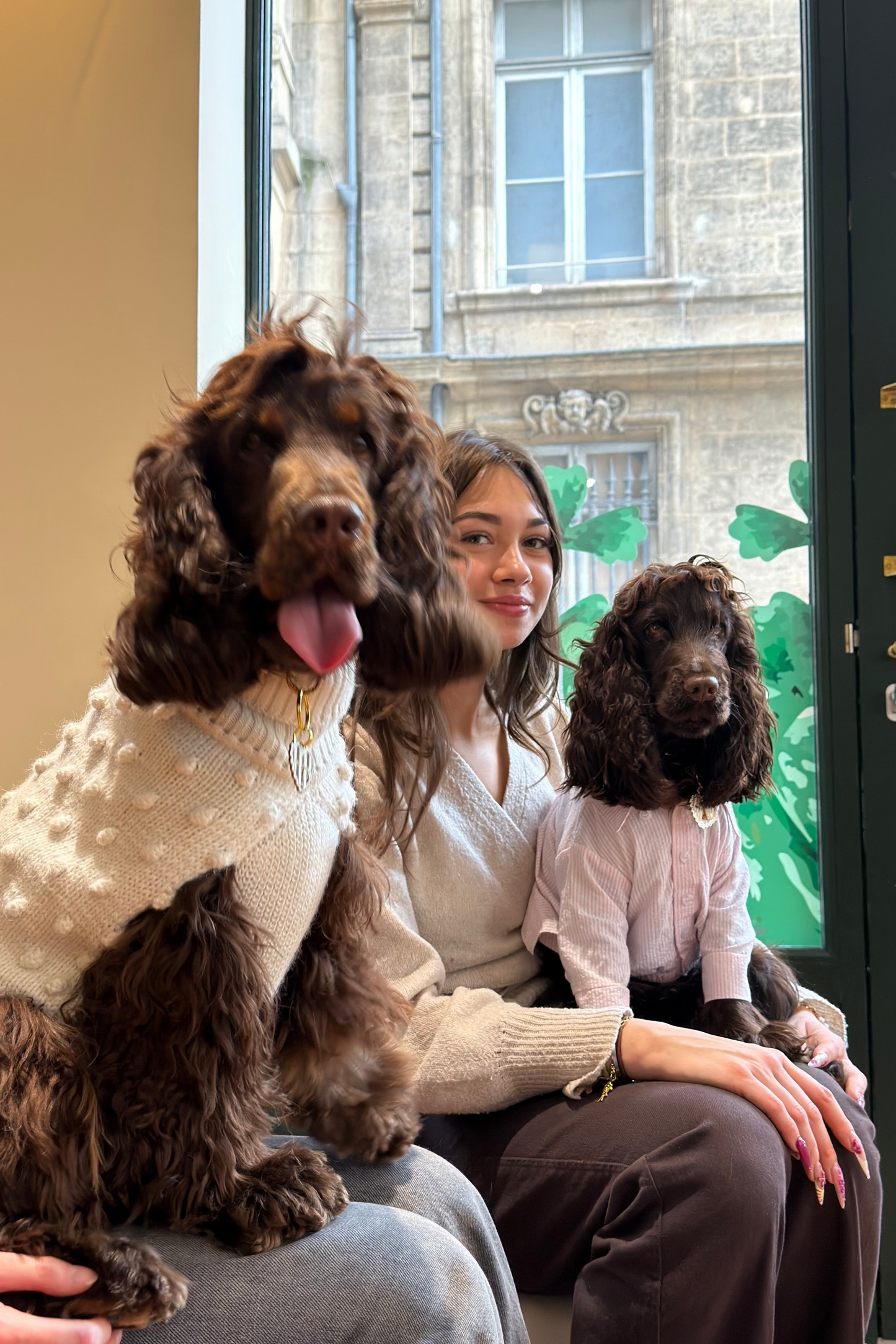 Two people with two dogs sitting together in front of a building.